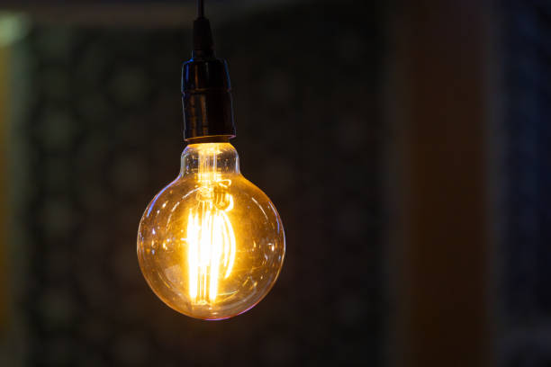 istock A light vintage bulb is lit up and hanging from a ceiling with dark background. 2188824608
