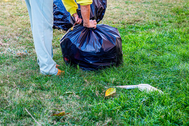 Woman collecting leaves from her backyard into a garbage bag
