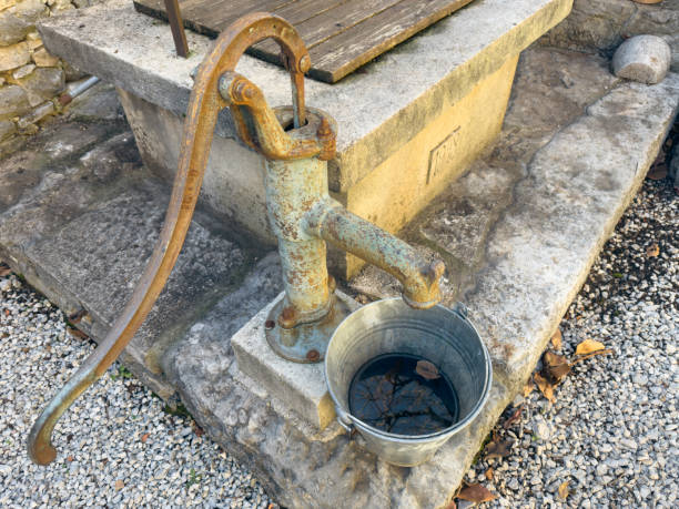 istock Rusty Hand Pump with Metal Bucket on Stone Platform 2188825252