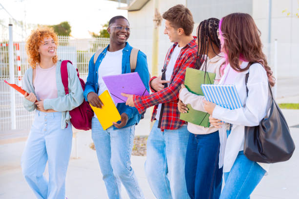 istock Group diverse students walking together with notebooks outdoors on a sunny day 2188826095