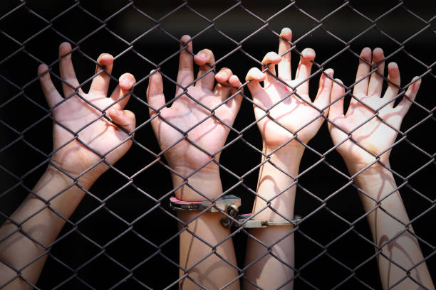 istock Hands Reaching Through a Chain Link Fence with Handcuffs 2188826517