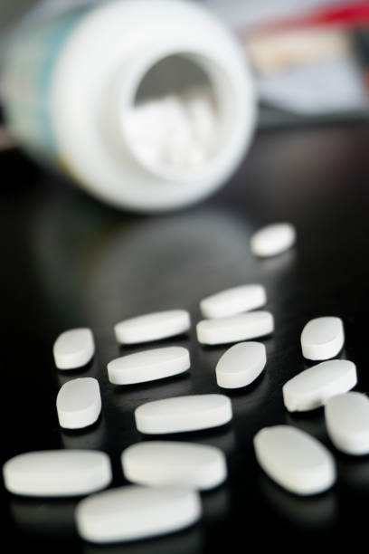 istock White tablets scattered near an open bottle on a dark surface 2188827610