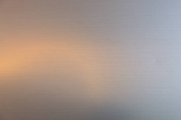 stainless steel background texture with yellow light reflection.