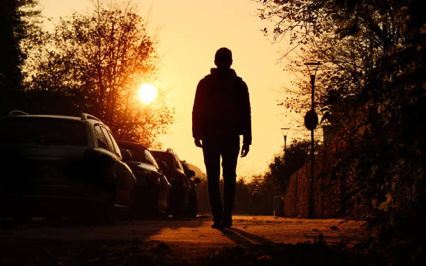 Silhouette of a man walking in the town, tranquil backlit scene stock photo
