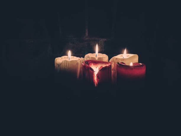 Lit, old wax candles in an old brick fireplace. Leaking wax, stearin. Spider's web. Warm, mysterious atmosphere