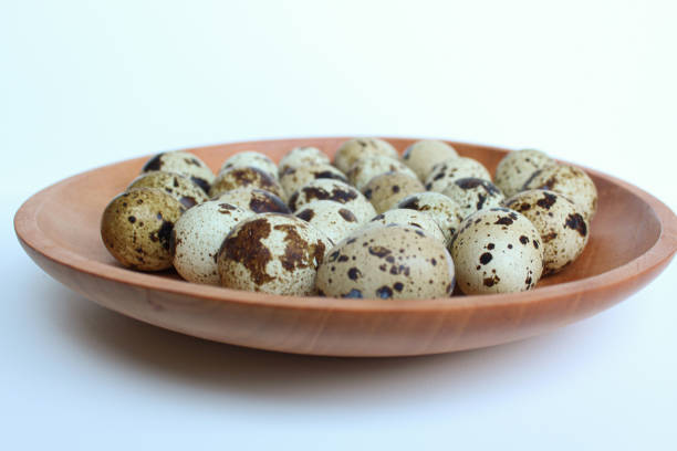 Quail eggs on wooden plate, isolated on white background.