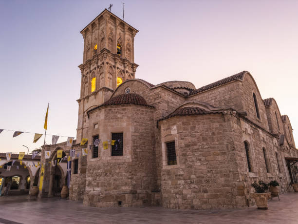 Iconic stone church with a bell tower and decorative flags, showcasing historical architecture in Larnaca, Cyprus.