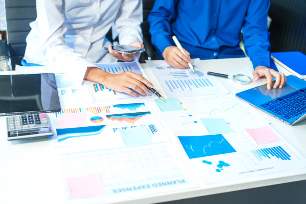 istock Two Asian business woman working and talking at a table with documents, a graph, and a digital tablet. They are focused on analysis, business planning, and collaborative discussions 2188846857