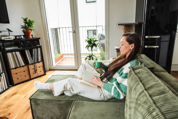 istock Young Woman Enjoying Tea and Reading a Book at Home 2188848949