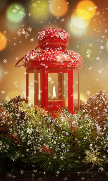 istock Vertical Christmas scene featuring a red lantern with a glowing flame on a tree, bokeh lights in the background, and falling snow, creating a romantic holiday atmosphere 2188851332