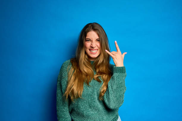 istock Young woman showing rock and roll hand gesture on blue background 2188851520
