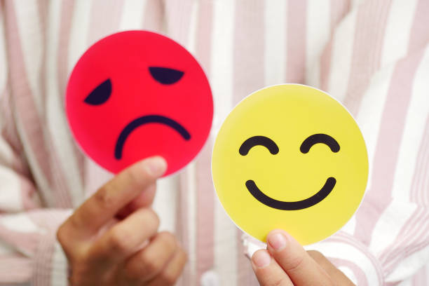 istock Hands holding a blurred card sad face and happy face. Concept of introversion, bipolar, depression, mental health, split personality, mood swings. 2188857785