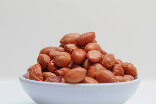 Peanuts or groundnut, or goober, or monkey nut. Peeled peanuts with thin red skin. Isolated on white background