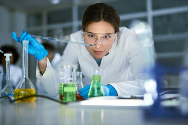 female scientist examining liquid in laboratory. - chimiste photos et images de collection