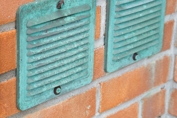 Copper ventilation grilles against a brick wall