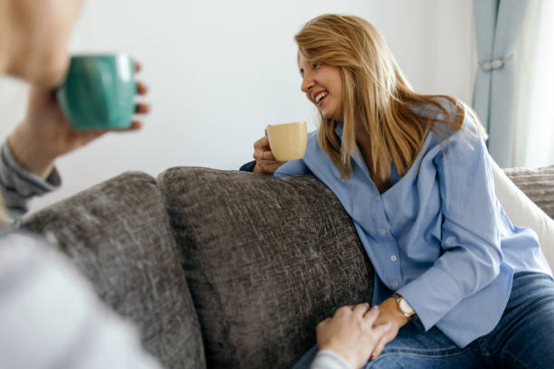 istock Two women sitting together on sofa and talking 2188867181