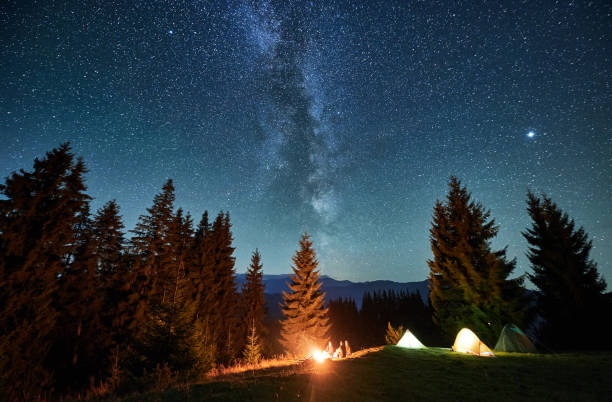 istock Night starry sky over mountain hill with camp tents and trees. 2188869512