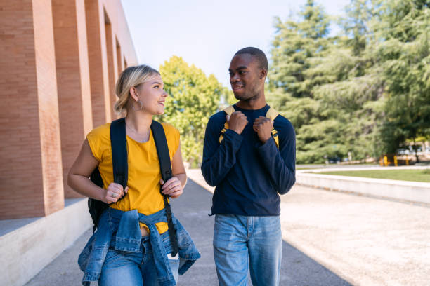 Two cheerful university students walking and talking on campus
