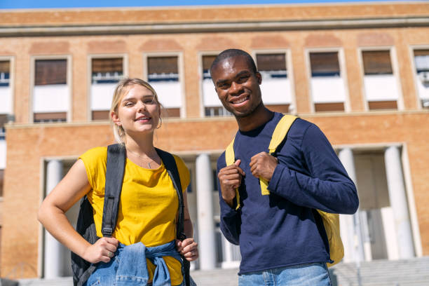 istock Two smiling university students standing in front of their college building 2188874646