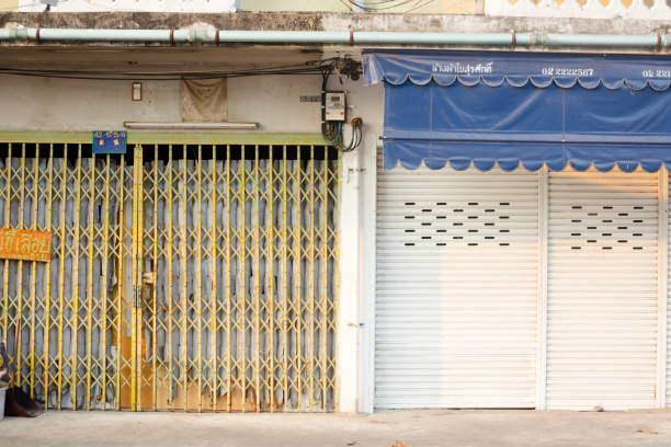 Different closed jalousie typesof small stores in row houses in street Soi Borommabanphot in backside of Wat Saket in Bangkok Pom Prap Sattru Phai. In street are old row houses. Upper floors are restored with new windows and air cons
