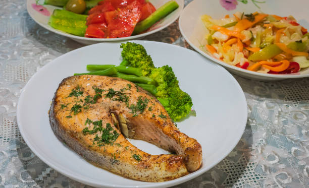 Oven baked Norwegian Atlantic Salmon steak. Salmon with herbs and boiled vegetables on a white plate.
