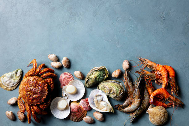 Top view of gourmet seafood served on white plates over a wooden table, featuring freshly prepared lobster halves, large prawns, oysters, and crab legs. The composition highlights a luxurious and indulgent seafood meal, perfect for fine dining, celebrations, or upscale restaurant menus.