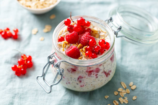 istock Overnight oats with fresh raspberries and red currants in glass jars. Blue textile background. Close up. 2188883965