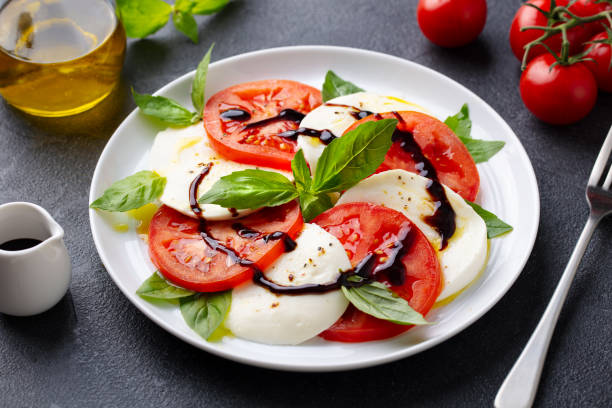 Caprese salad with tomatoes, mozzarella cheese, basil. Close up. Grey background.