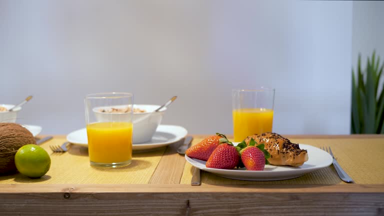 Breakfast at home with fresh strawberry, croissant and orange juice served on wooden table. Calm and relaxing morning on vacation.