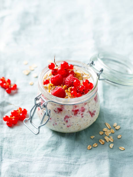 istock Overnight oats with fresh raspberries and red currants in glass jars. Blue textile background. Copy space. 2188885268