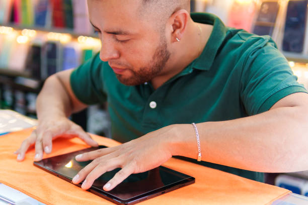 Phone repairman applying screen protector to tablet computer in his workshop