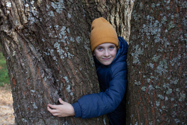istock Little boy hugging huge trunk of oak tree. Close up. 2188893259