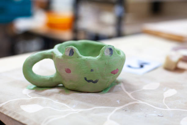White coffee mug in the shape of a cat with pink ears, close-up on a white background.