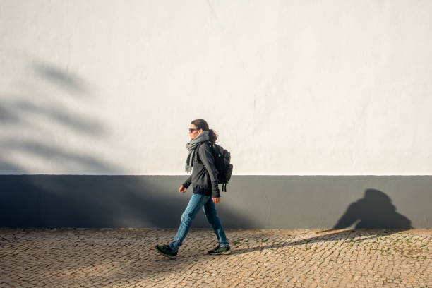 istock woman with a backpack walking by a white wall, exercise. 2188898275