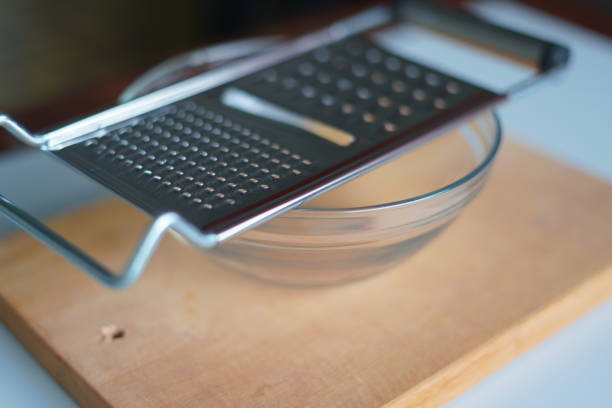 grater and glass bowl on a chopping board