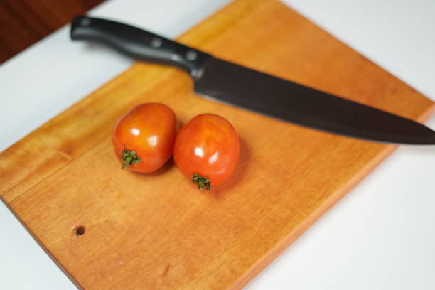 Close-up of a stainless steel knife cutting an orange pepper into slices