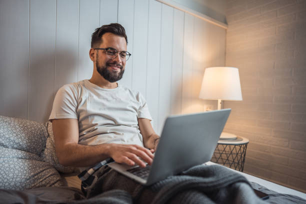 istock Work in comfort, man with laptop relaxing in bed 2188902674
