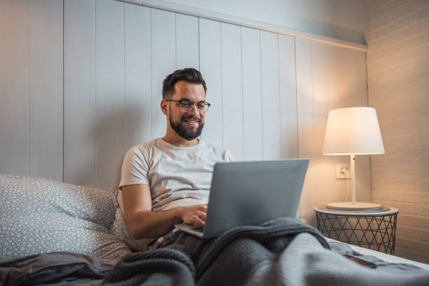 istock Work in comfort, man with laptop relaxing in bed 2188902677