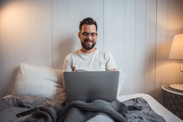 istock Work in comfort, man with laptop relaxing in bed 2188902690