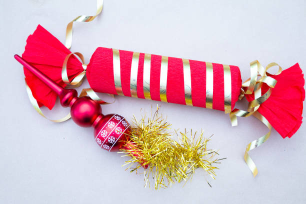 A beautifully designed red and gold striped Christmas cracker that features a charming red ornament nestled inside for festive occasions