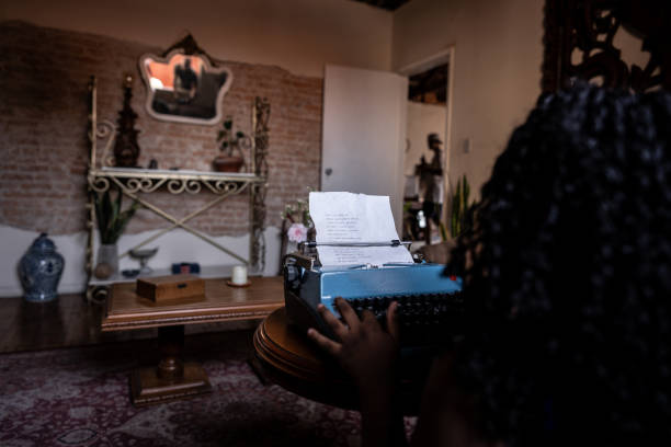 overhead writer typing vintage typewriter surrounded by dried leaves and candlelight, red beret and fingerless gloves, textured