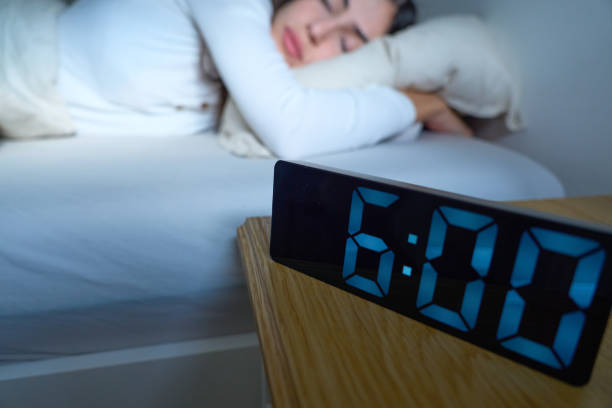 istock Woman sleeping in bed, alarm next to her 2188904498
