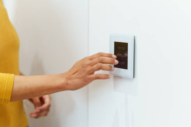 istock Hispanic Female Adjusts Thermostat in Modern Home 2188909669