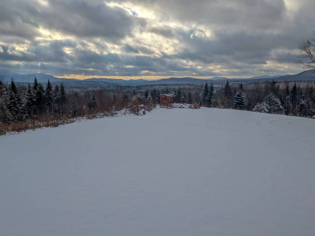 Snowy field with mountains and clouds in the background