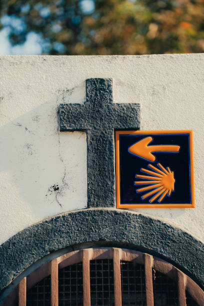 The scallop shell pointing right on the wall with a Catholic cross.