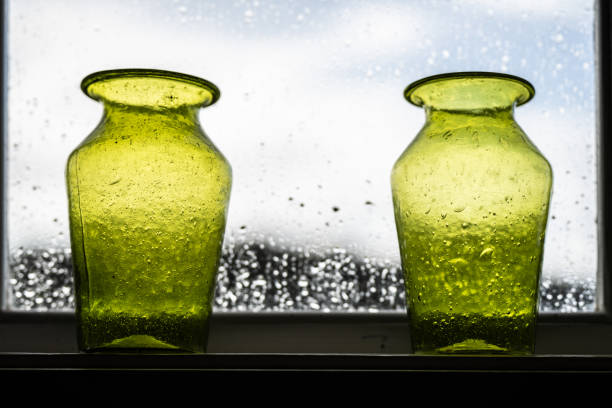 Green hand made glass vases in a window.