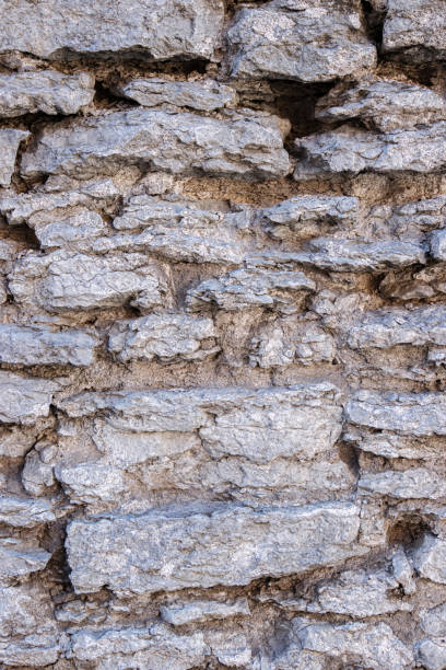 istock Weathered rough aged gray stone wall texture with rugged, coarse uneven irregular rocks, stacked together, revealing an old historic architectural style 2188917578