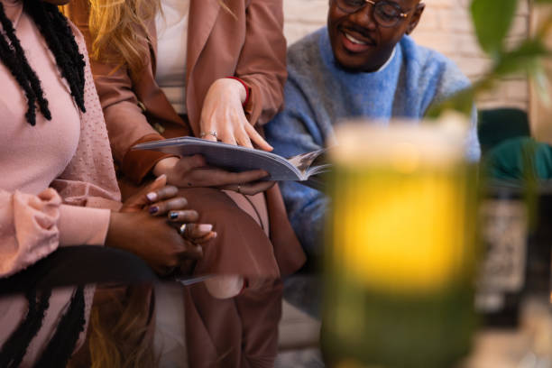 istock Friends in a cafe looking through a book 2188920365