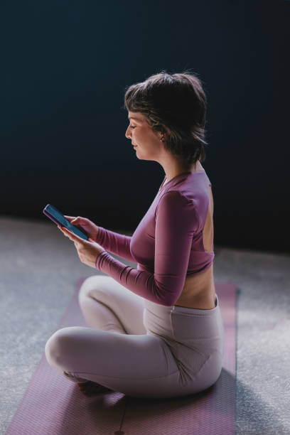 istock Woman Sitting on Yoga Mat Using Smartphone in Serene Setting 2188922782