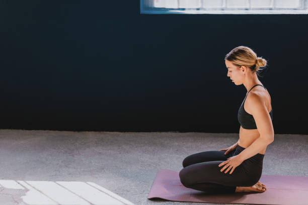 istock Young Woman Practicing Yoga Meditation on a Mat in Minimalist Studio 2188922815